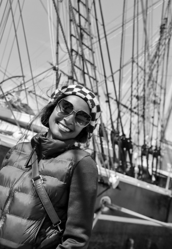 Alice Njambi on the deck of a tall ship, smiling in sunglasses and a patterned beanie.